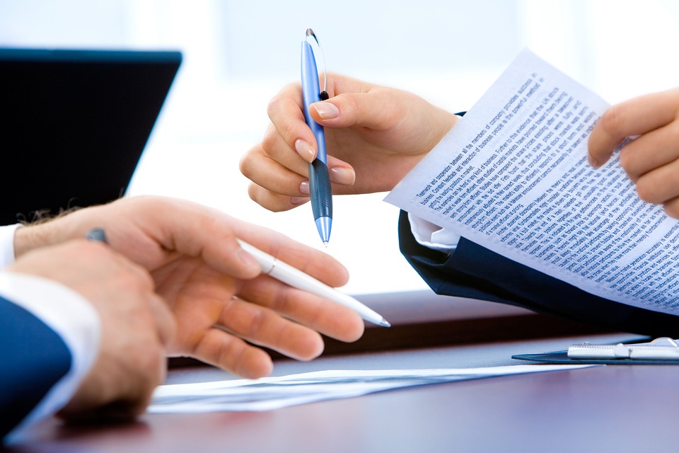 pessoas analisando documento com uma caneta na mão para assiná-lo